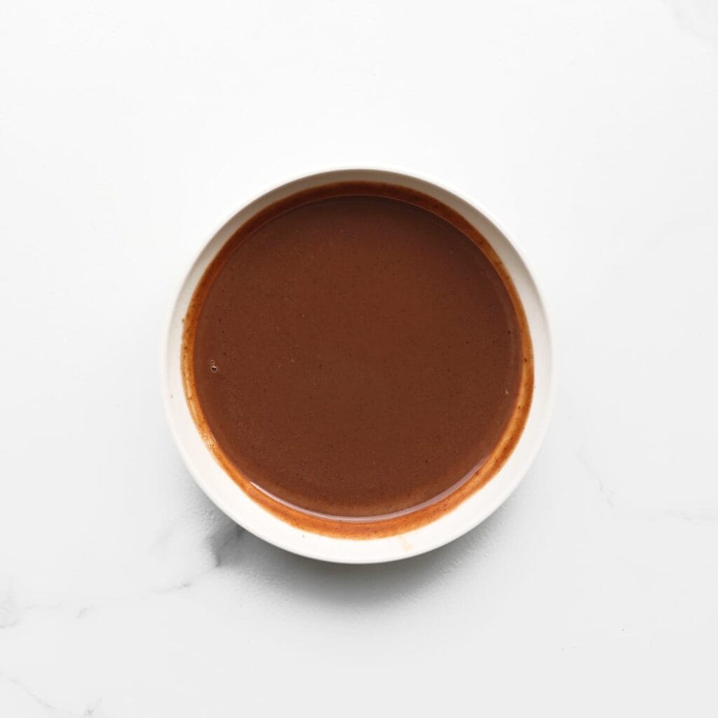 Verwarm de melk in een pan tot het kookt. Zet daarna het vuur uit en voeg de chocoladepasta toe. Roer het geheel tot een glad mengsel en laat het afkoelen tot kamertemperatuur.