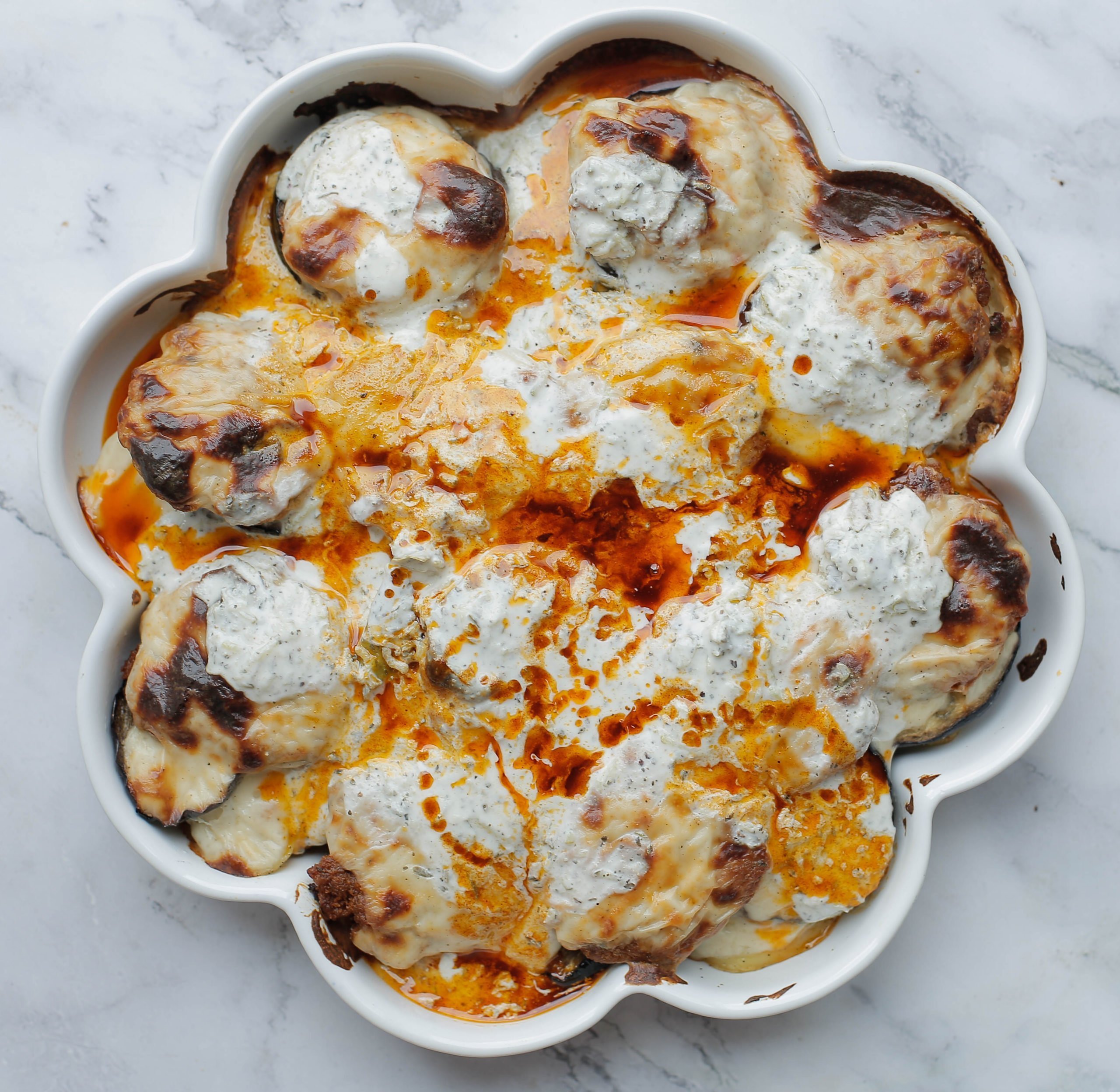 Yoghurtsaus en paprikasaus toevoegen aan de aardappelschijven, aubergineplakjes en het gehakt