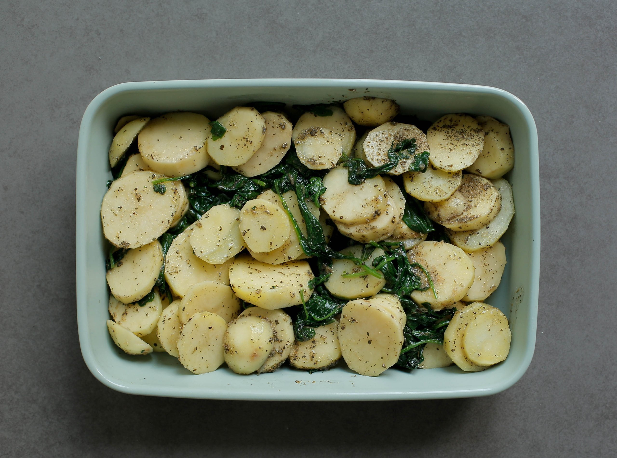 Aardappelmengsel met spinazie en kruiden in een ovenschaal