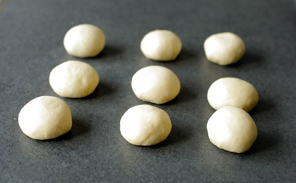 Verdeel het deeg in 9 stukken en vorm ze mooi rond (65 gram per bol).