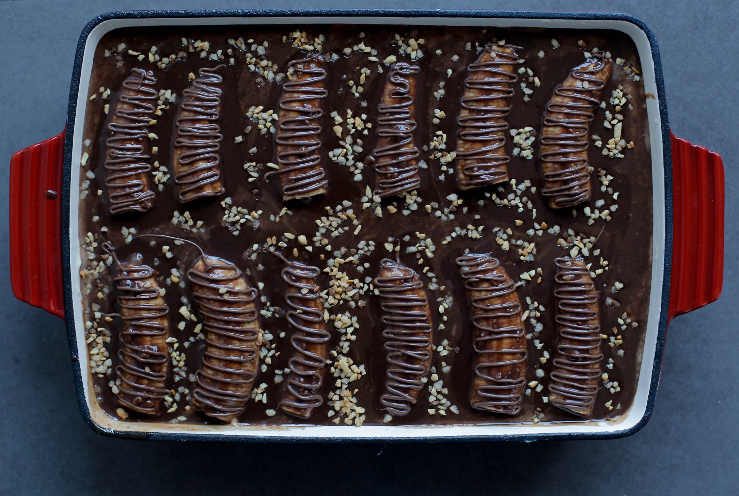 Chocoladecake met room, banaan en ganache garneren met gehakte hazelnoten