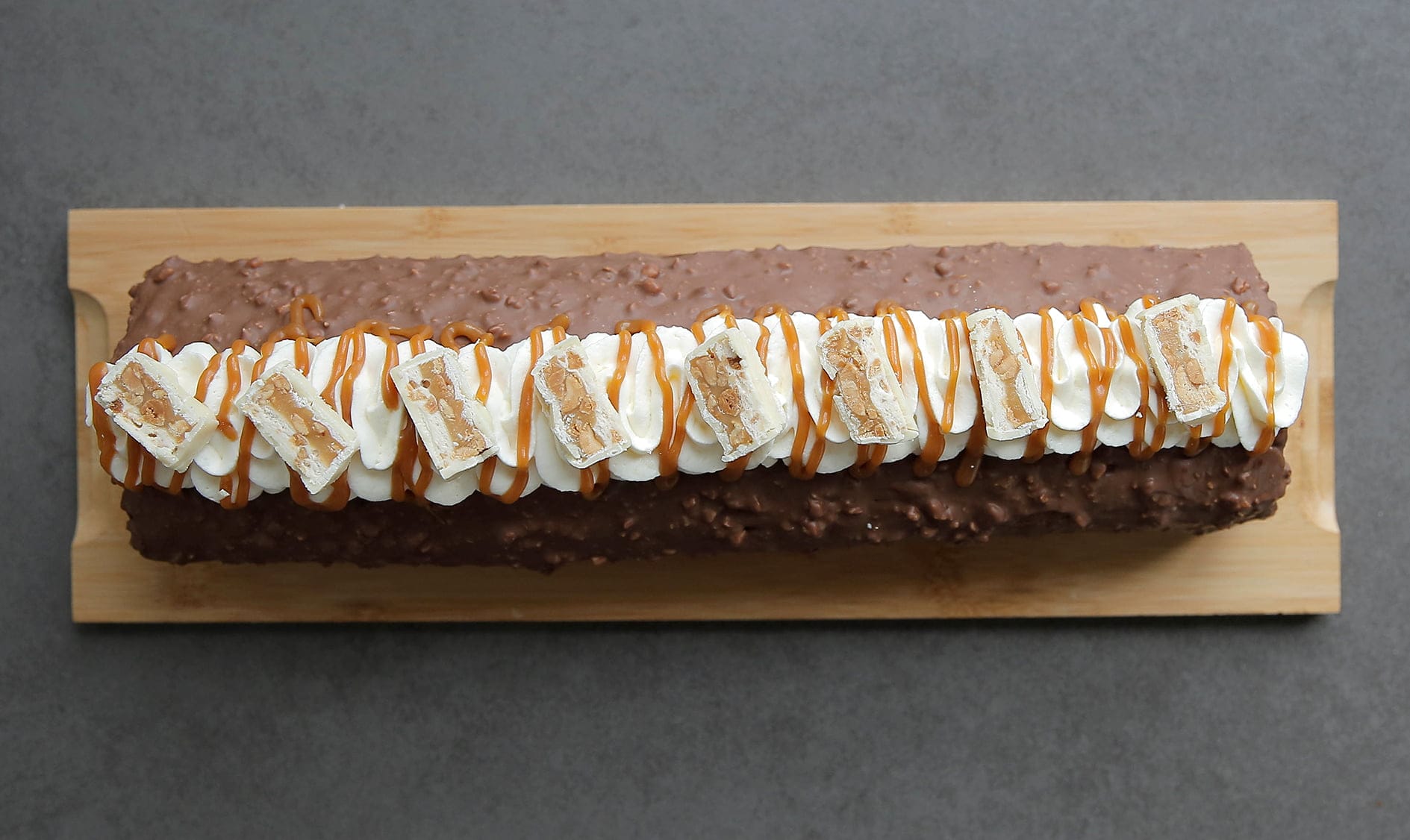Snickers rolcake garneren met slagroom, karamel en stukjes snickers