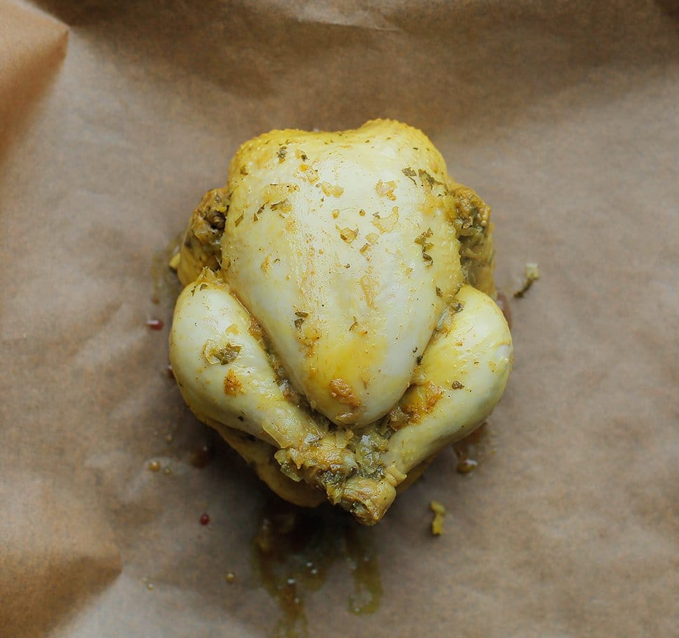 Gekookte kip op een bakpapier beklede bakplaat leggen