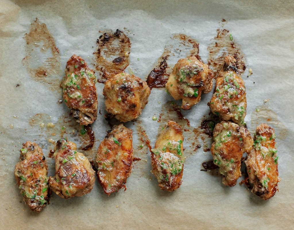 Haal de kippenvleugels voorzichtig uit de oven. Smeer ze nogmaals in met het kruidenbotermengsel voordat je ze serveert voor extra smaak.