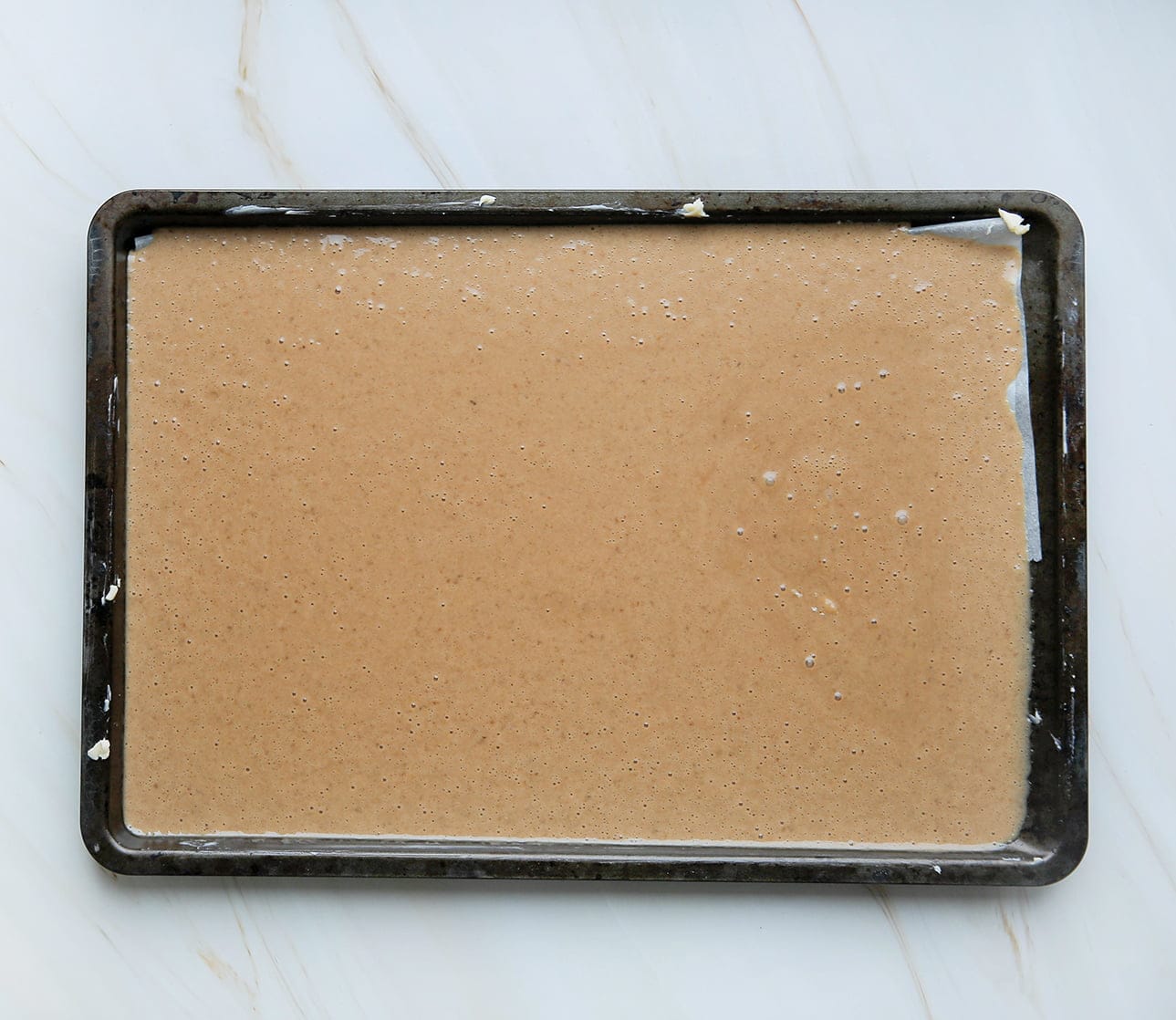 Cakebeslag uitsmeren over bakplaat