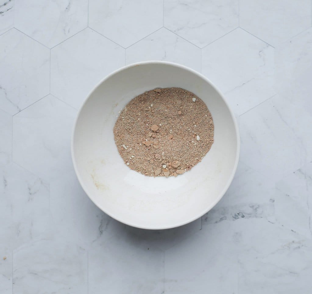 Doe de ras el kouzina, currypoeder, paprikapoeder, korianderpoeder, het zout, de knoflookpoeder, zwarte peper en cayennepeper in een kom. Meng goed.