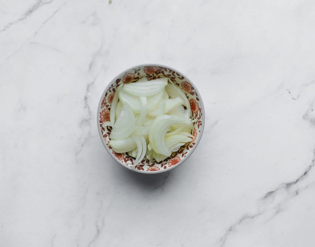 Pel en snijd de gele ui in halve ringen.