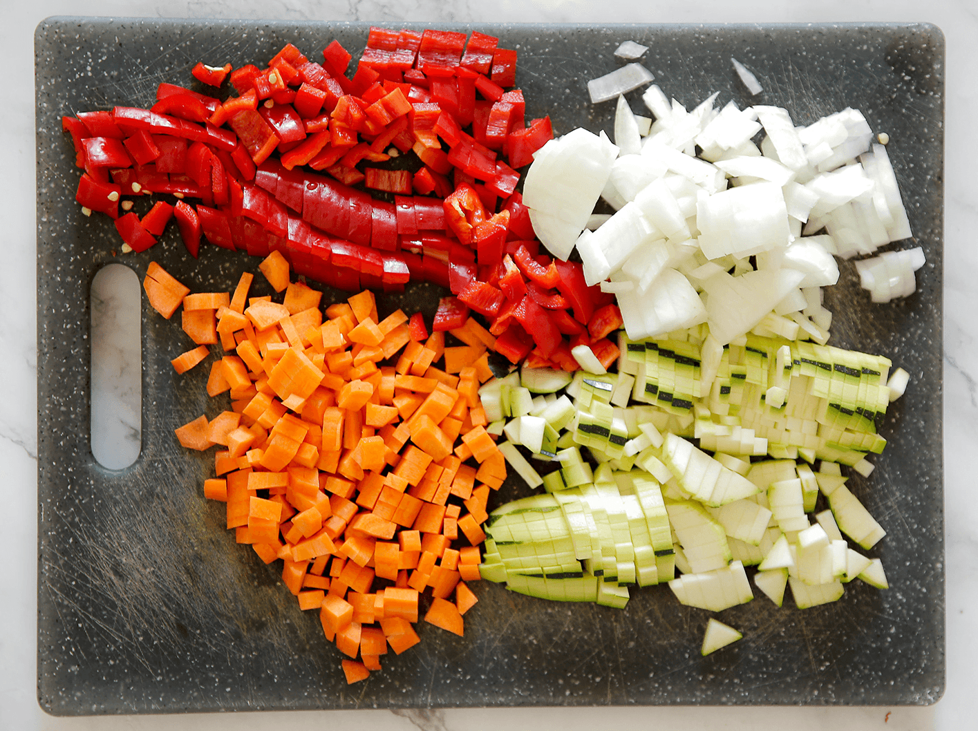 Puntpaprika, wortel, courgette en gele ui klein snijden