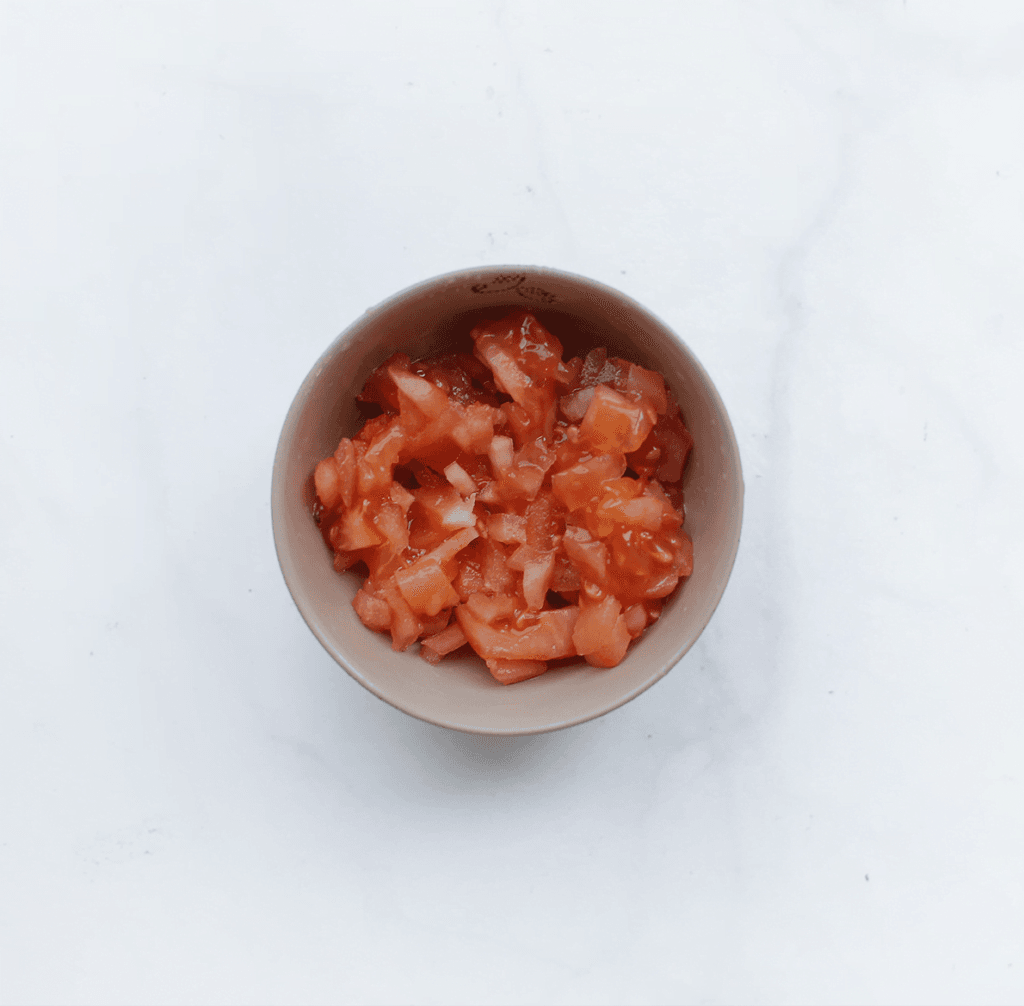 Ontvel de tomaten. Snijd de helft van de tomaten niet al te fijn. 