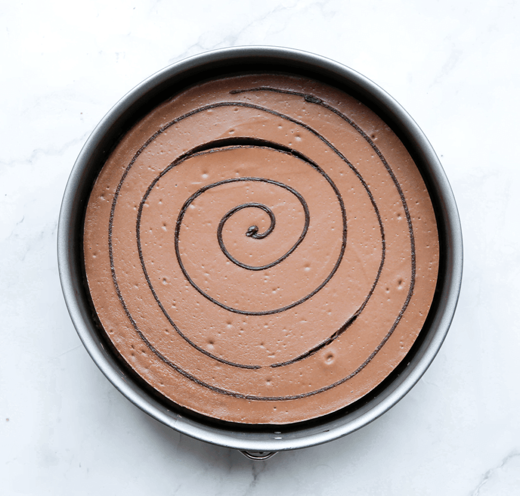 Zet de brownie-nutella cheesecake in een voorverwarmde oven op 125 ℃. Bak 50-55 minuten of tot de zijkanten stevig zijn en het midden nog een beetje wiebelt. Schakel de oven uit en laat de brownie-cheesecake 1 uur in de oven liggen. Dit voorkomt dat de cheesecake inzakt/scheurt. Haal de brownie-nutella cheesecake uit de oven en leg, afgedekt in de koelkast. Cheesecake is de volgende dag het lekkerst.