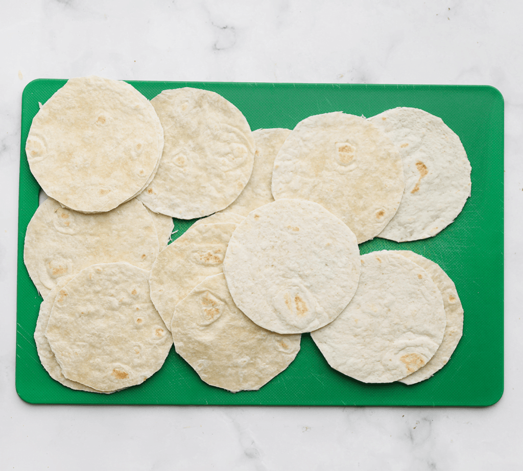 Neem een wrap, vouw deze dubbel en daarna weer tot een kwart gevouwen wrap. Knip er rondjes uit. Herhaal deze werkwijze (je kunt de restanten gebruiken voor het maken van tortillachips).