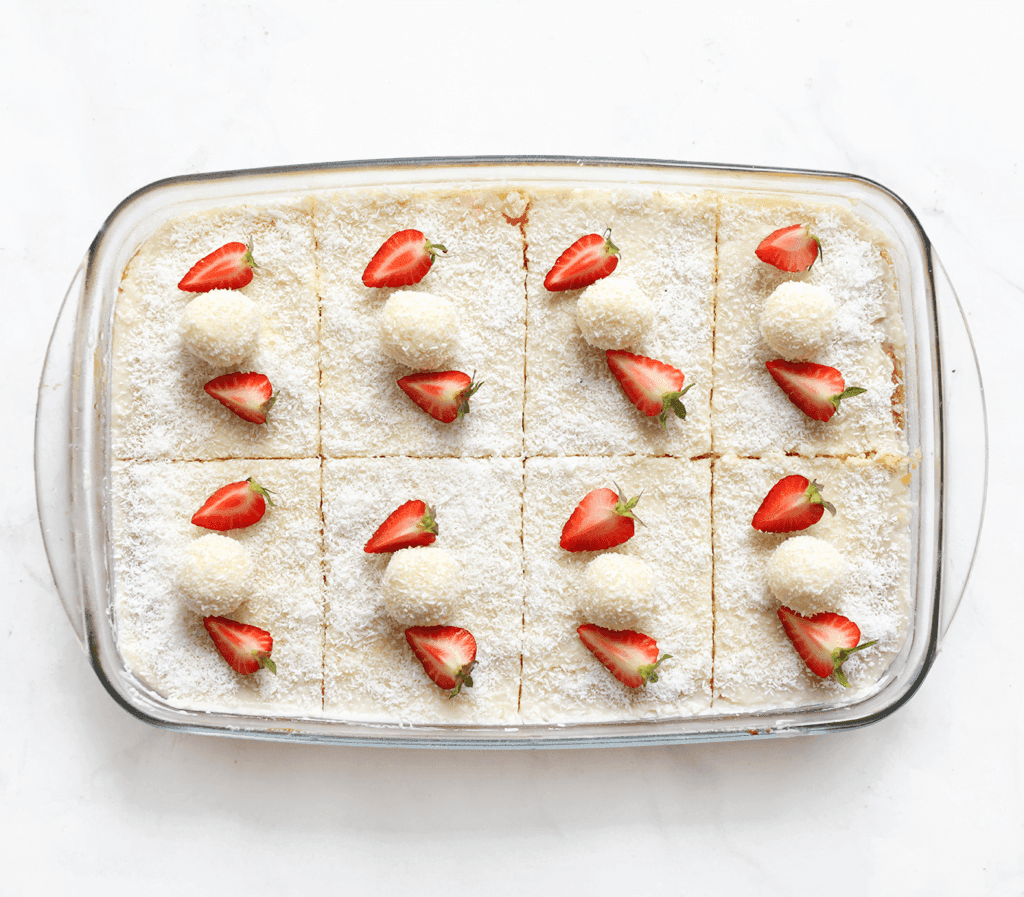 Garneer de kokoscake met friszoet aardbeien en kokosbollen.