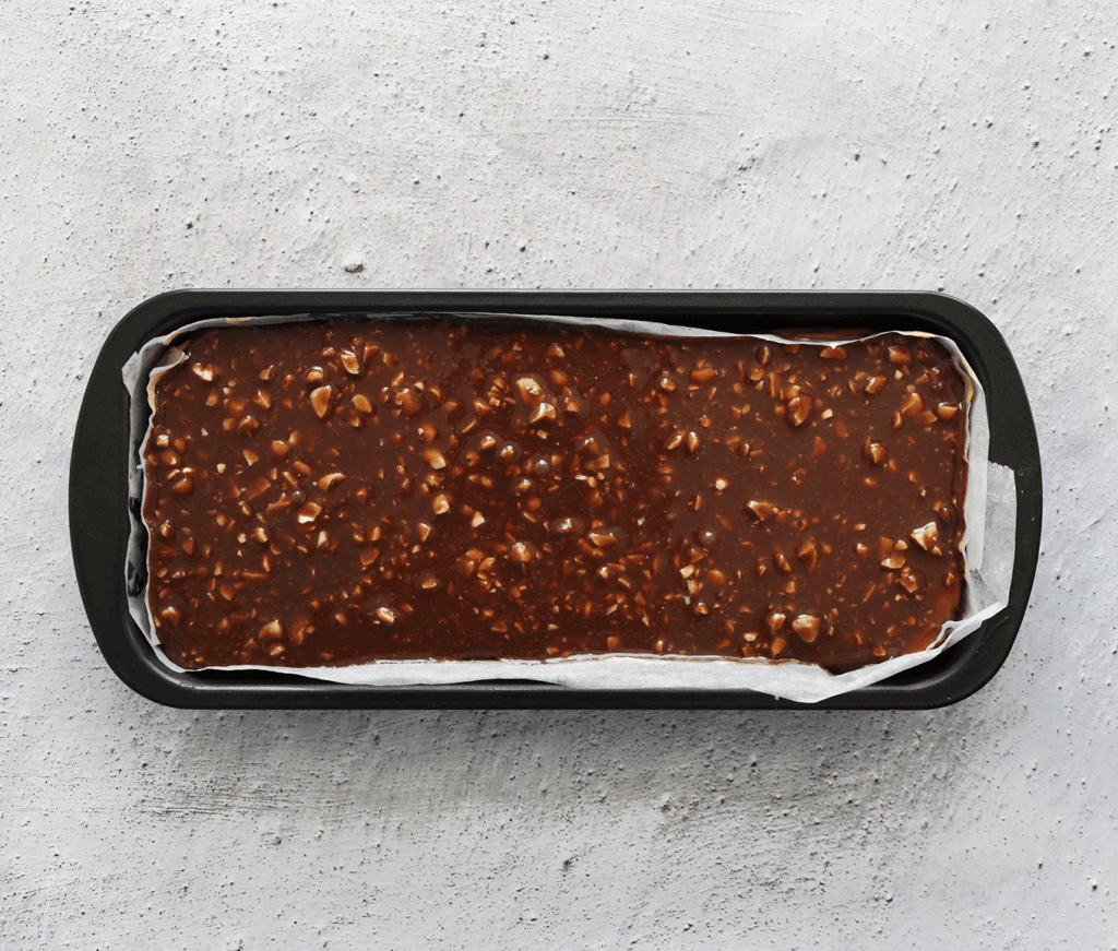 Verdeel het chocolademengsel over de Snickers-cheesecake en zet deze in de koelkast totdat de topping stevig is.