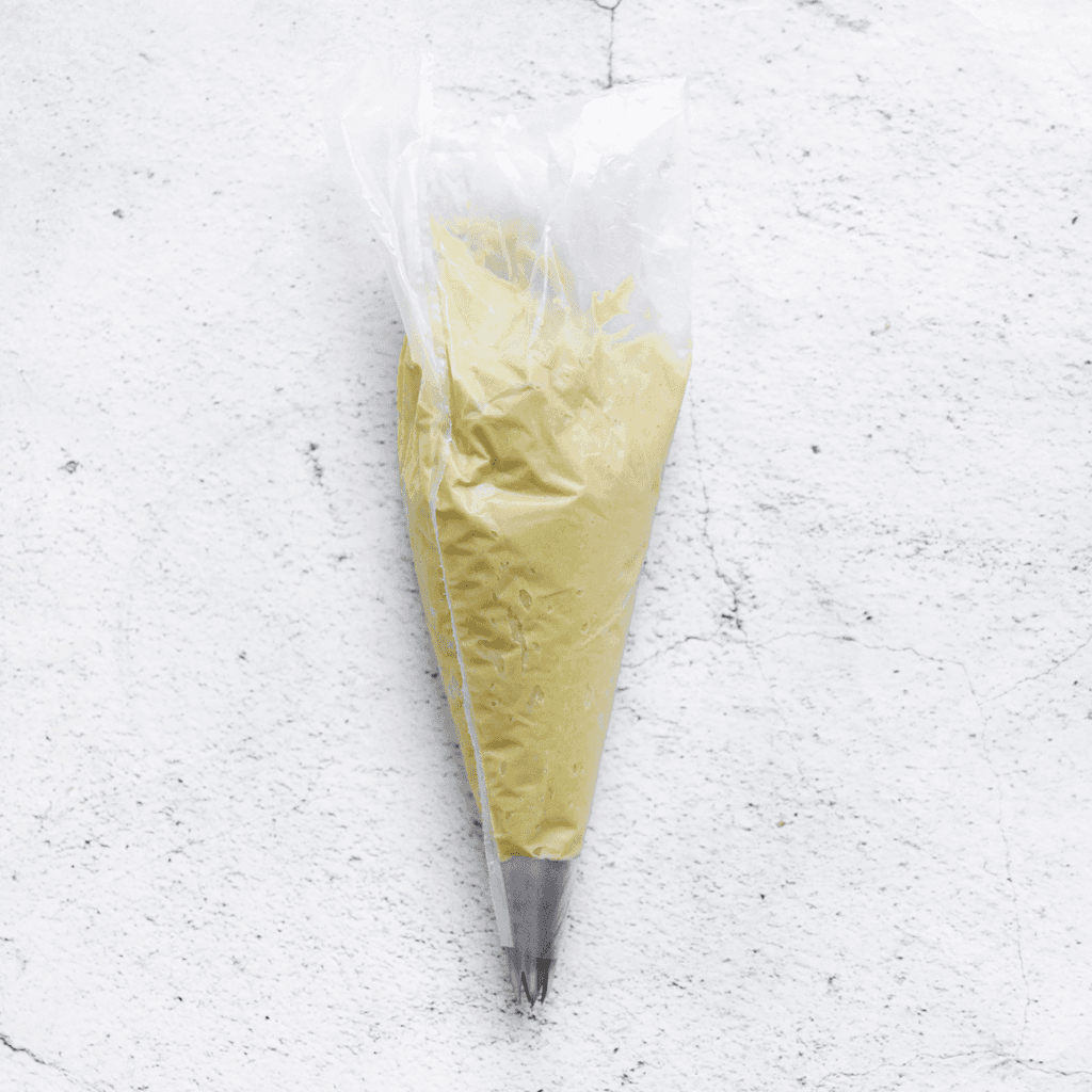 Schep de pistacheroom in een spuitzak en zorg ervoor dat je een spuitmondje aan het uiteinde bevestigt.