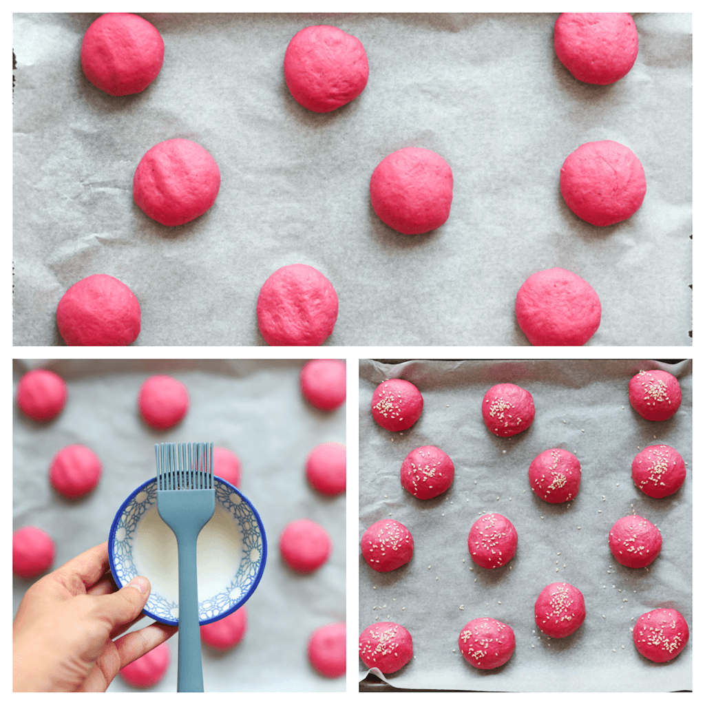 Leg de deegbollen op een bakplaat met bakpapier. Bestrijk ze met melk en garneer ze met sesamzaad. Laat de rode bietenbroodjes 30 minuten rijzen, of tot ze in omvang zijn verdubbeld.