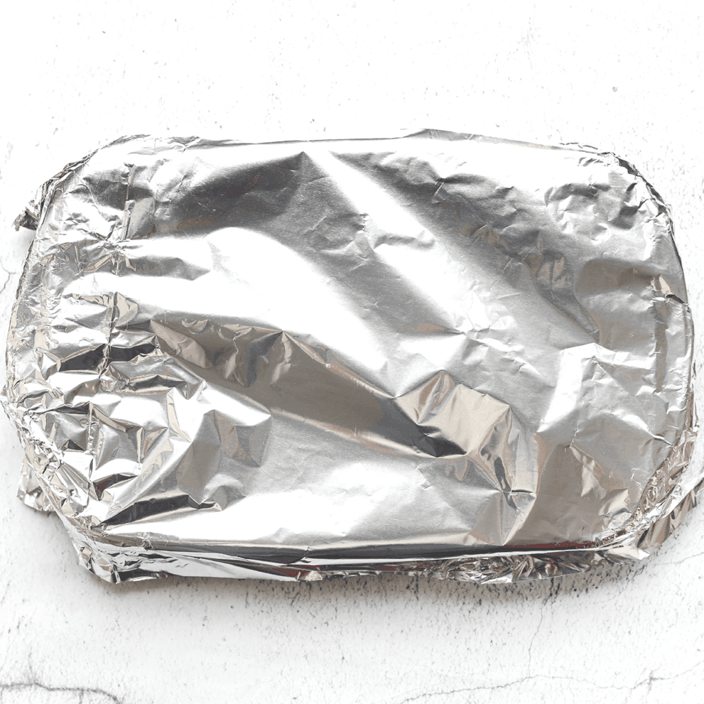 Bedek de ovenschaal met een vel bakpapier en daaroverheen een vel aluminiumfolie.
