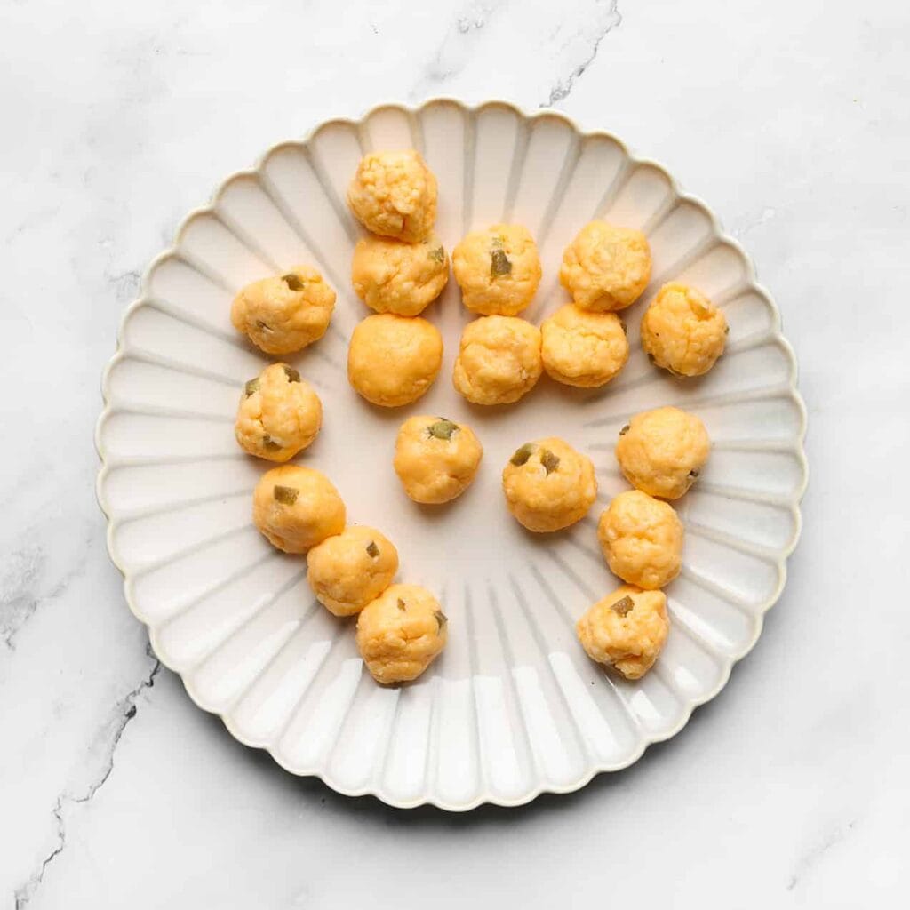 Neem een portie van het kaasmengsel van ongeveer 7 gram en vorm het tot een bol. Herhaal deze stap voor de rest van het mengsel.