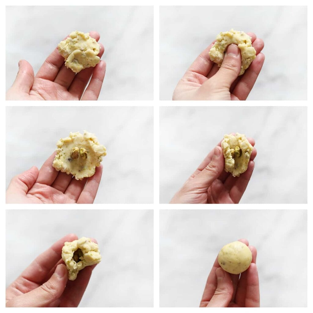 Neem een kleine hoeveelheid koekjesdeeg en plaats twee pistachenoten in het midden. Vervolgens sluit je het deeg rondom de pistachenoten en rol je het geheel tussen je handpalmen tot een gladde bol.