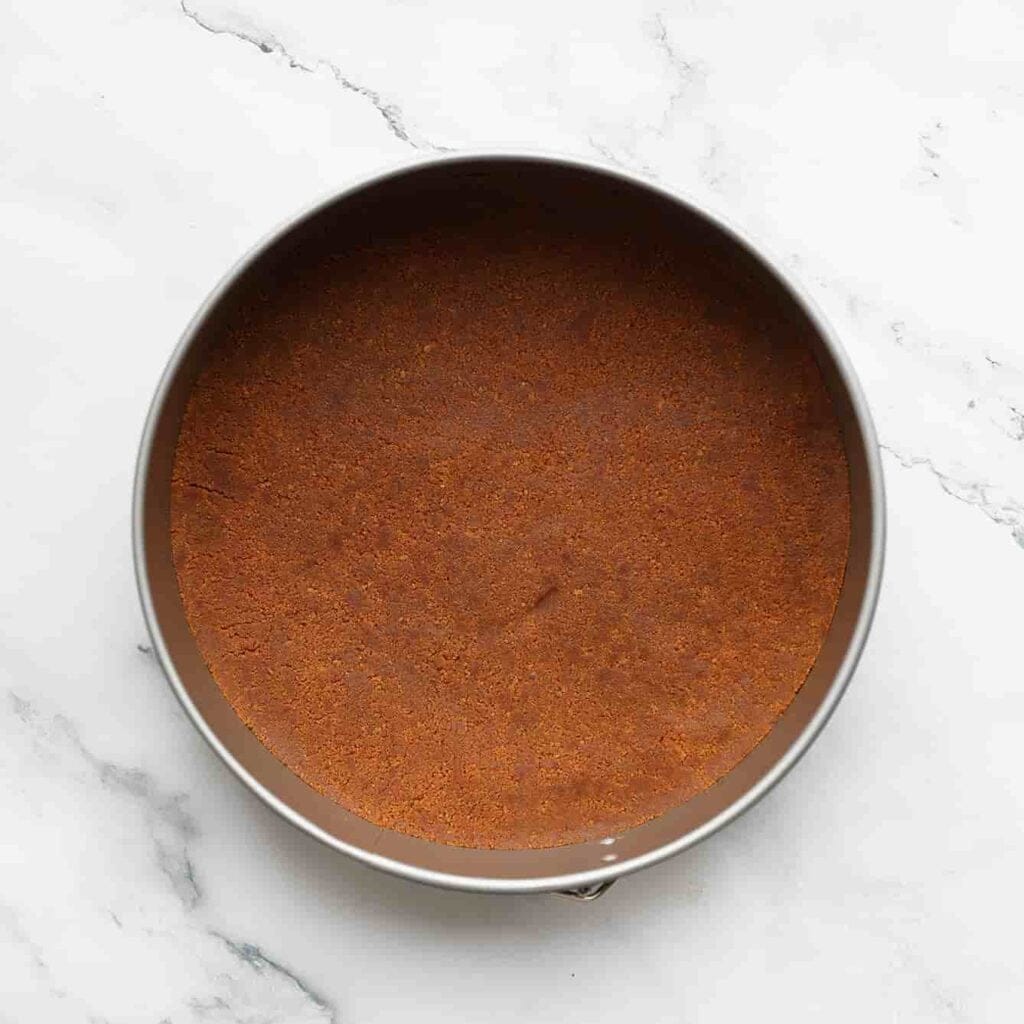 Verdeel het koekjesdeeg over de bakvorm en druk deze goed tegen de bodem aan (gebruik als hulpmiddel de onderkant van een lepel). Leg het even weg in de koelkast.