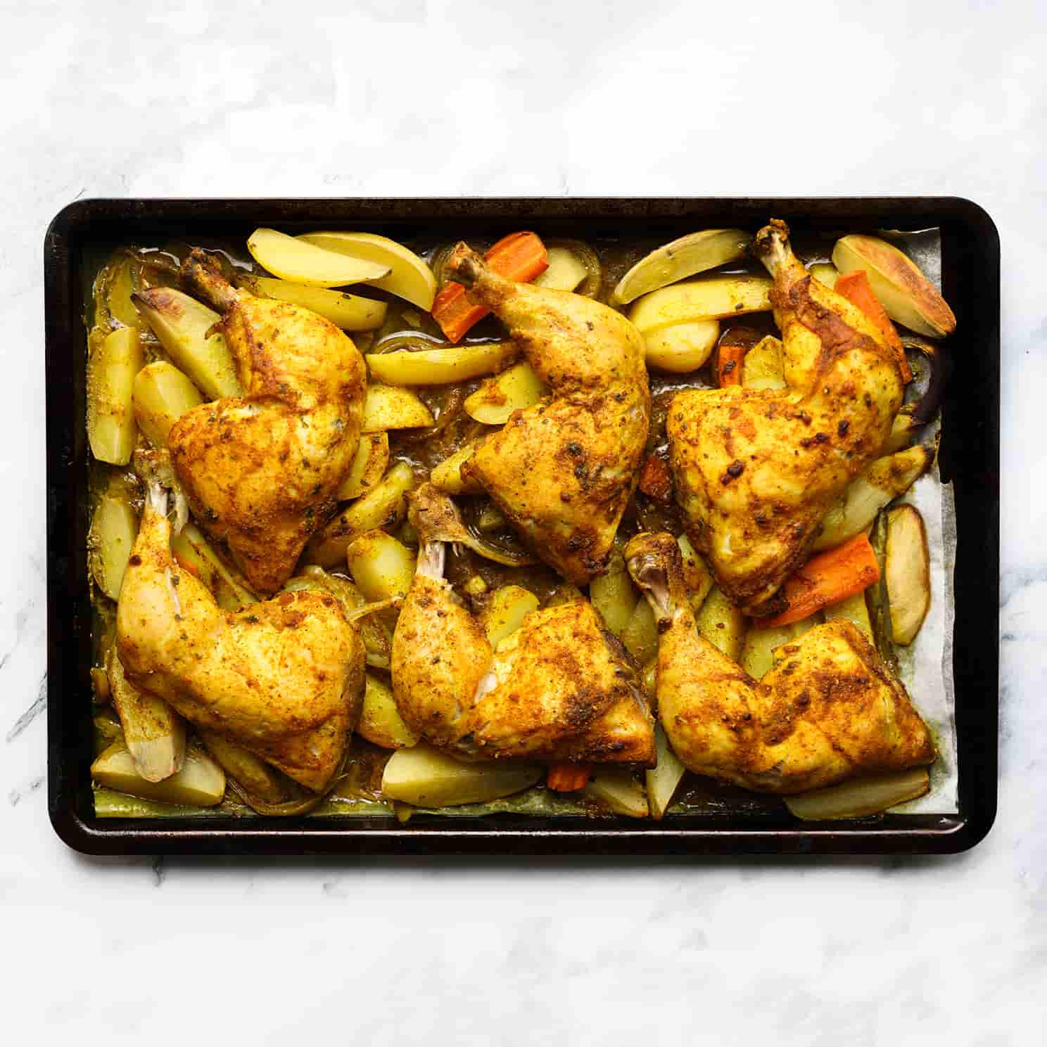 Traybake met kippenbouten en groenten bakken in de oven