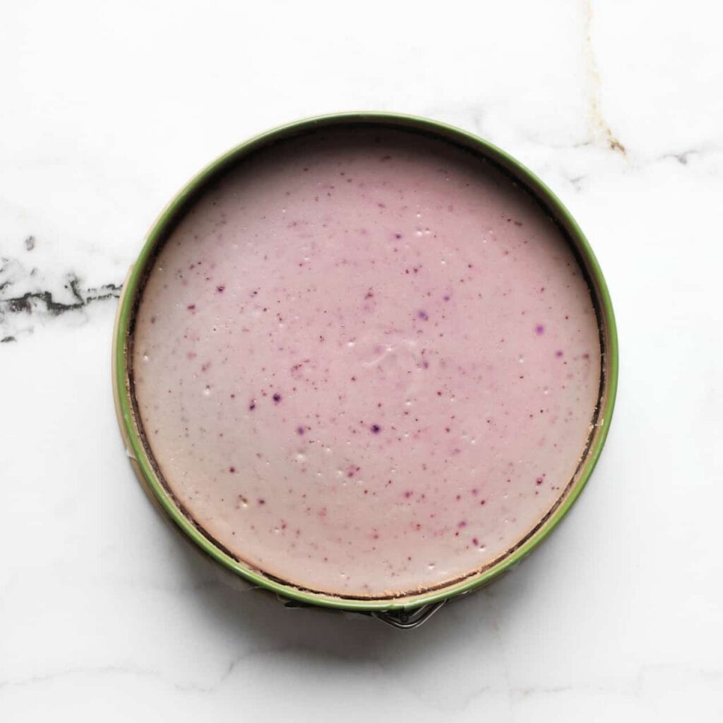 Zet de bosbessen-cheesecake in een voorverwarmde oven op 125 ℃. Bak 60-65 minuten of tot de zijkanten stevig zijn en het midden nog een beetje wiebelt. Schakel de oven uit en laat de cheesecake 1 uur in de oven liggen. Dit voorkomt dat de cheesecake inzakt/scheurt.