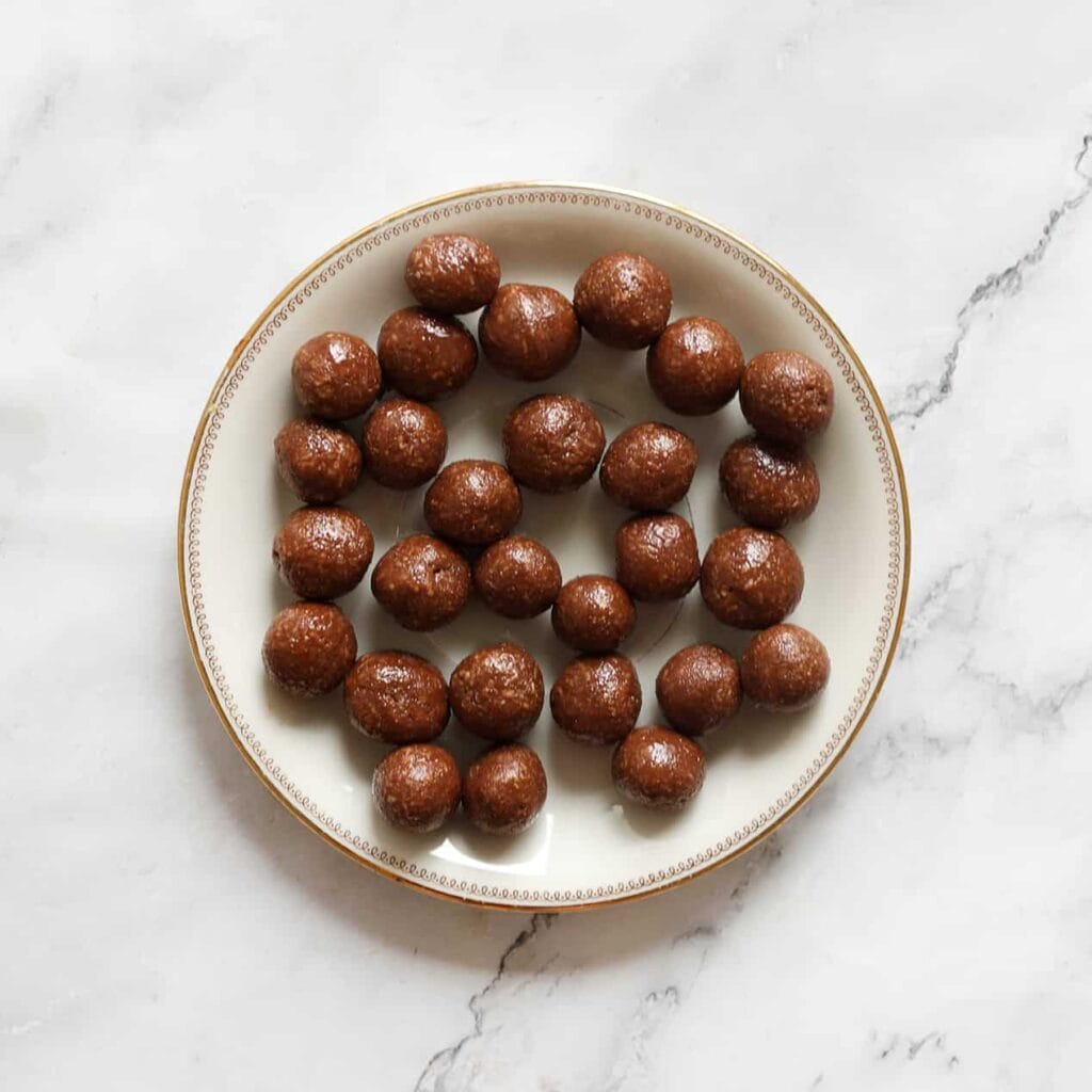 Wanneer het chocolademengsel stevig is, neem je er wat van en vorm je het tot een bol. Herhaal deze werkwijze voor de rest van het mengsel.