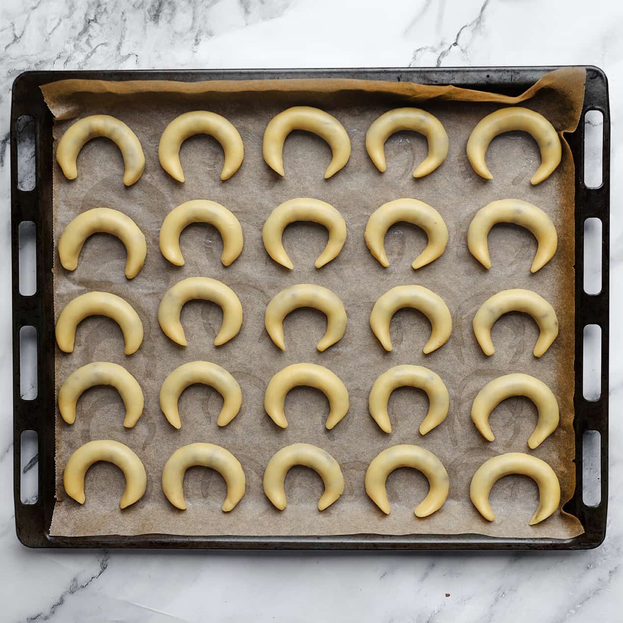 Halve maankoekjes op een bakplaat met bakpapier