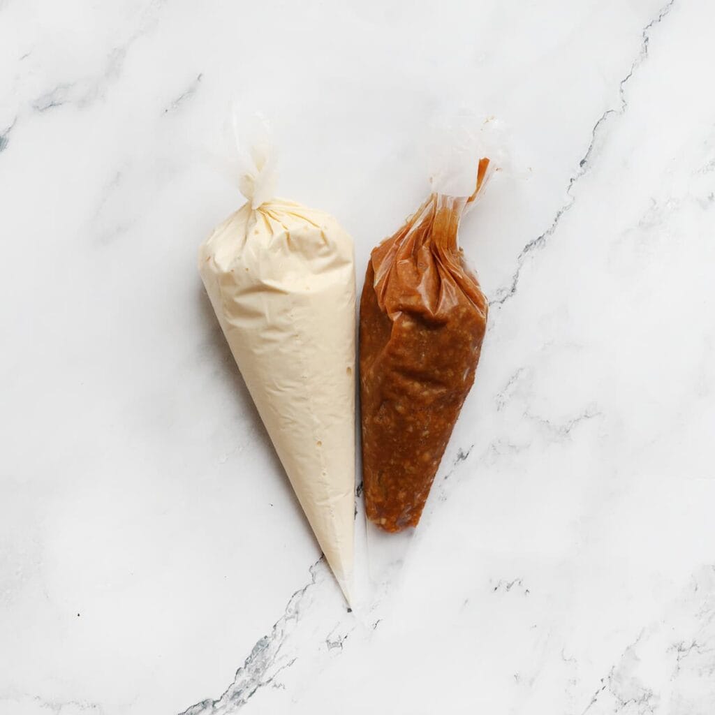 Doe het cheesecakebeslag in een spuitzak en doe hetzelfde met het pinda-karamelmengsel.