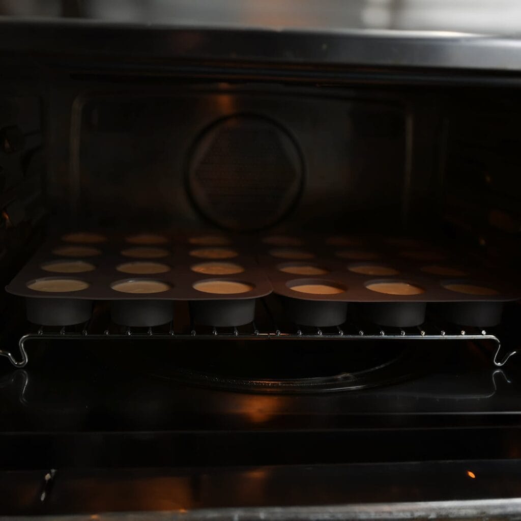 Zet de mini cheesecakes in een voorverwarmde oven op 115 °C. Bak 20-25 minuten. Schakel de oven uit en laat de mini cheesecakes langzaam afkoelen met de ovendeur dicht om barsten te voorkomen. Kortom, laat de cheesecakes 1 uur in de oven staan en zet ze daarna, afgedekt, in de koelkast (bij voorkeur een nachtje).