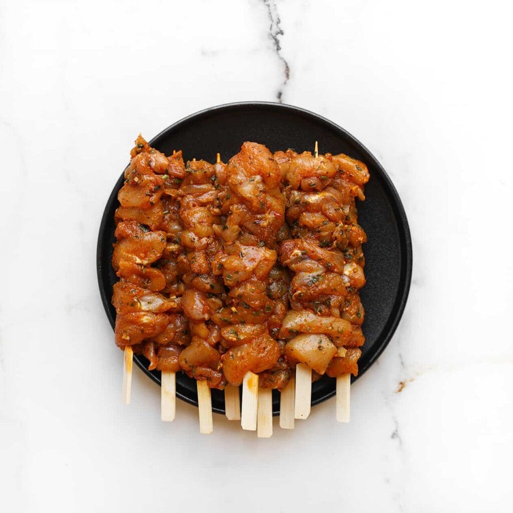 Maak de prikkers nat voor gebruik. Vul een glas met water en laat de prikkers daarin 20 minuten wellen. Rijg de kipstukjes aan de spiesjes.