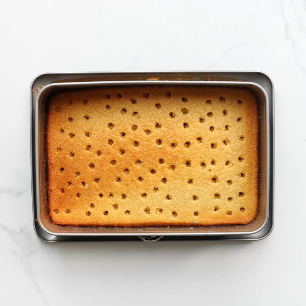 Gebruik de achterkant van een pollepel om gaten in de cake te maken.