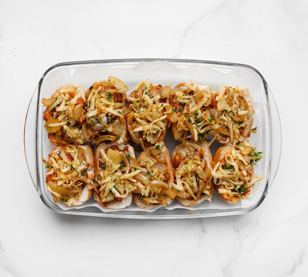 Verdeel het uienmengsel over de broodjes. Zet de ovenschaal in een voorverwarmde oven op 200 °C en bak 5-7 minuten, of totdat de kaas mooi gesmolten is.