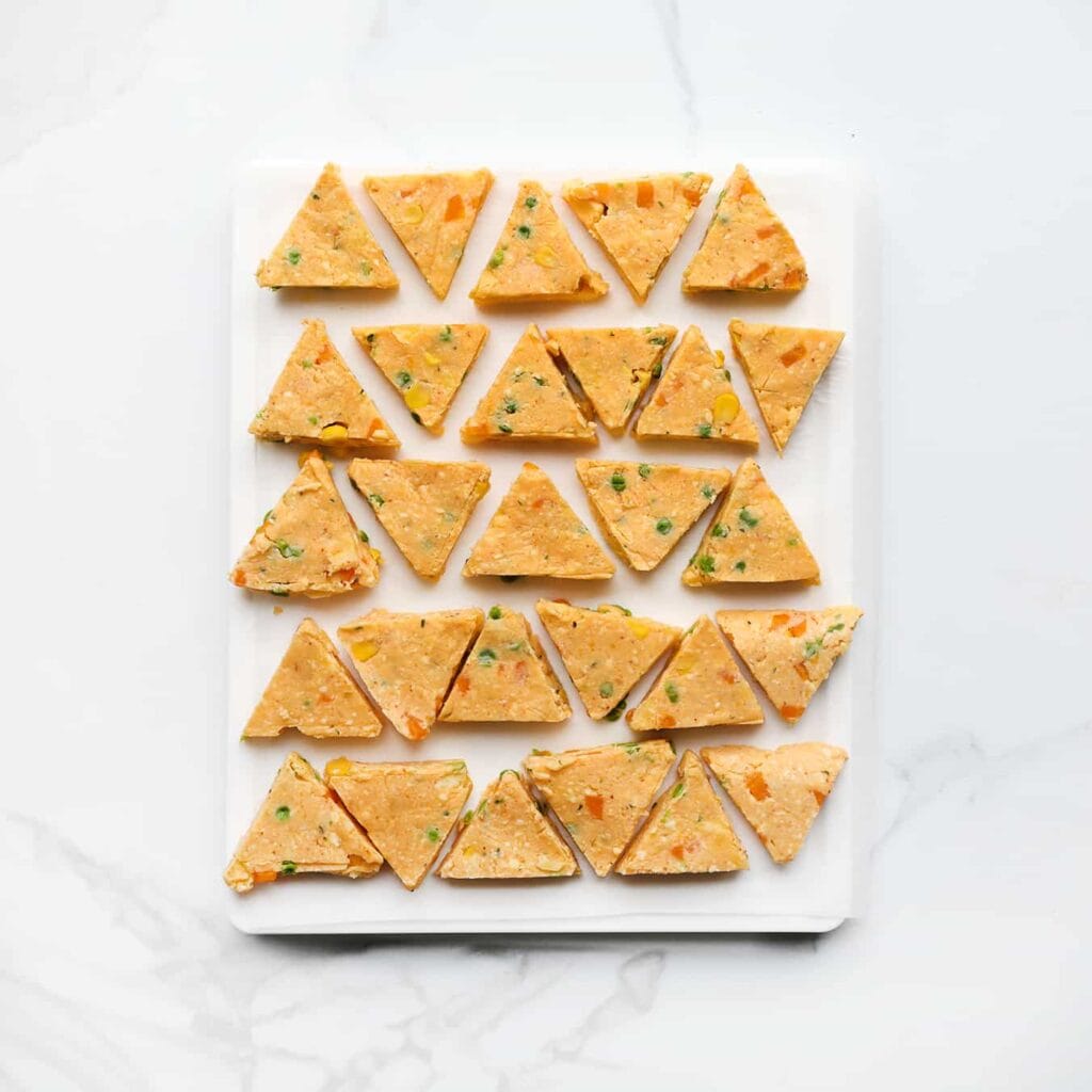 Haal de schaal uit de vriezer en snijd met een scherp mes de driehoekjes volledig los. Leg ze op een vel bakpapier.