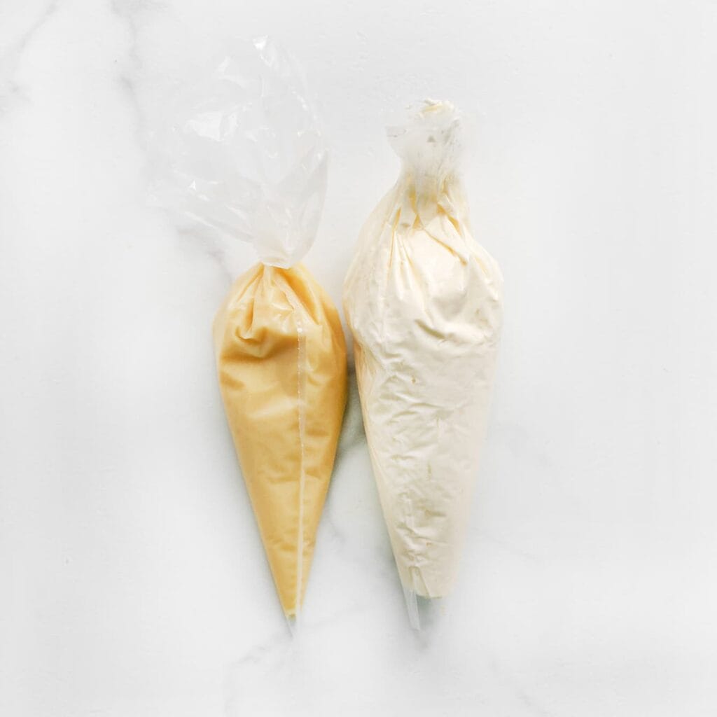 Vul aparte spuitzakken met de room en de witte chocoladeganache. Heb je geen spuitzakken? Dan kun je ook boterhamzakjes gebruiken.