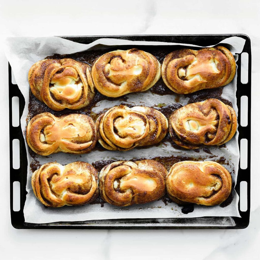 Zet de kaneelbroodjes in een voorverwarmde oven op 200 °C. Bak 12-15 minuten, tot ze mooi goudbruin zijn. Houd de baktijd goed in de gaten, want elke oven werkt anders. Haal de broodjes uit de oven, dek ze af met een schone theedoek en laat ze afkoelen.