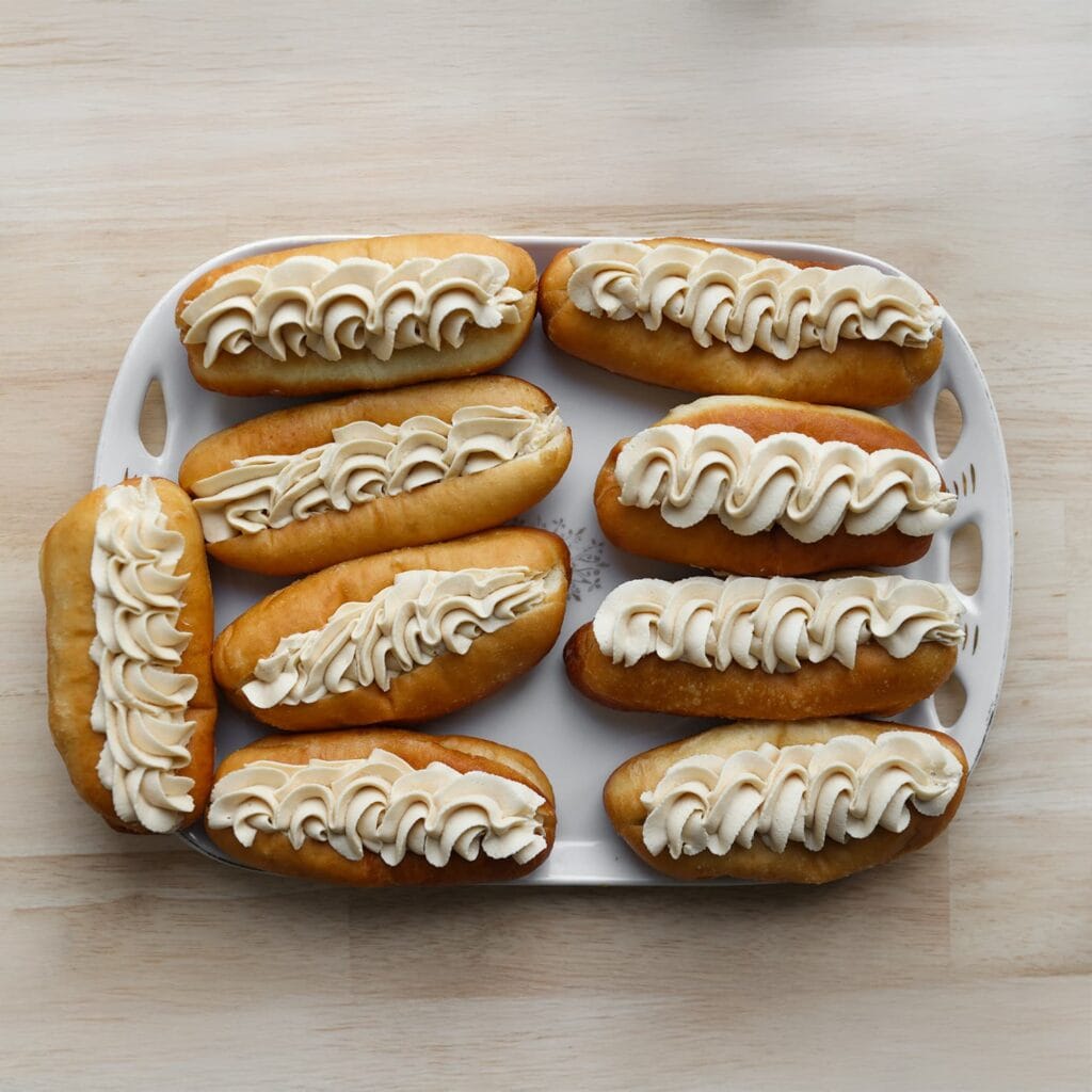 Snijd de donuts in het midden in en vul het midden met een beetje room. Spuit vervolgens een langwerpige toef room bovenop de lotusdonuts. Garneer naar wens met een extra laagje Biscoff-pasta en eventueel verse aardbeien.