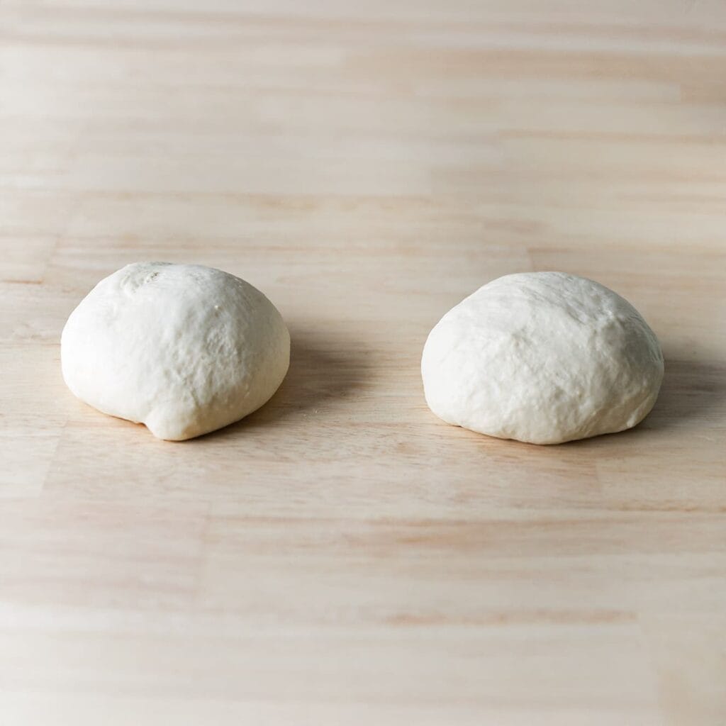 Druk de lucht uit het deeg en verdeel het in 2 gelijke stukken.