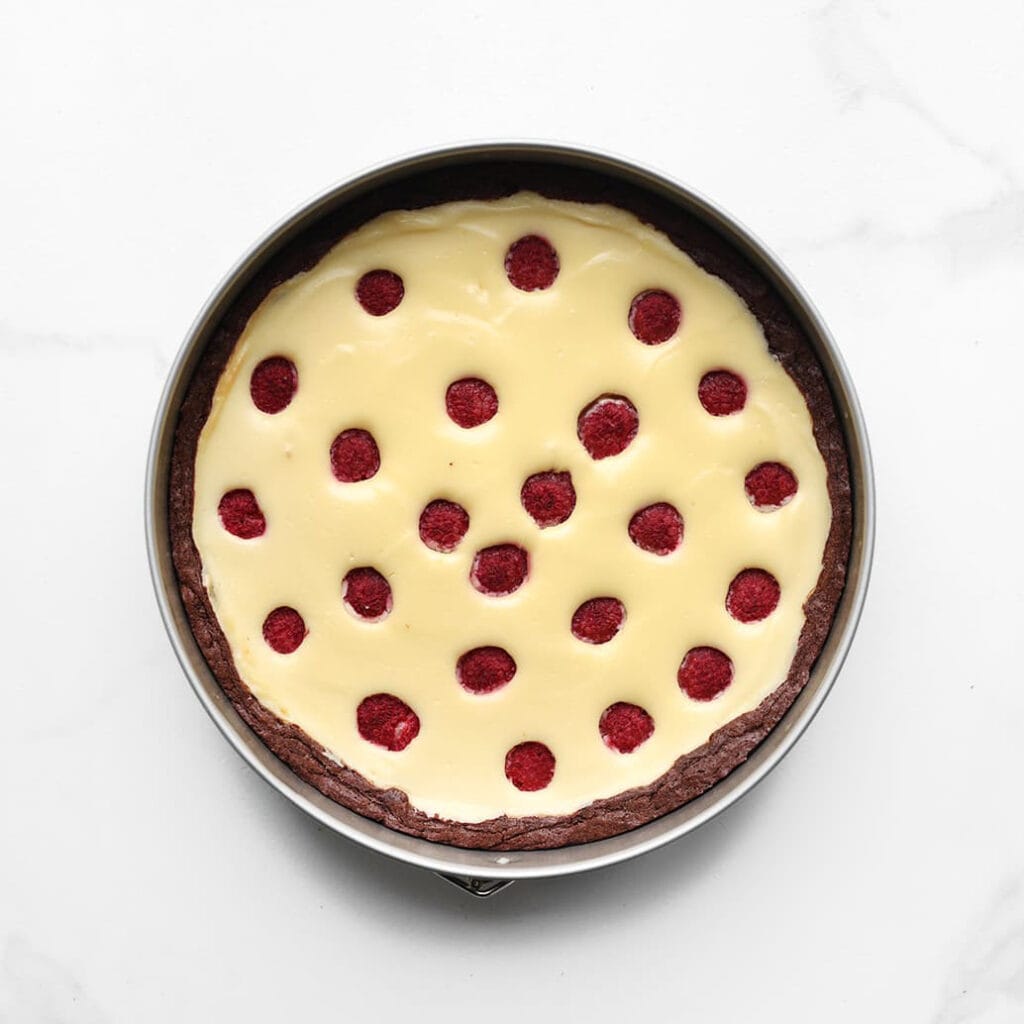 Zet de brownie-frambozencheesecake in een voorverwarmde oven op 125 ℃. Bak 60-65 minuten, of tot de zijkanten stevig zijn en het midden nog licht wiebelt. Zet de oven uit en laat 1 uur in de oven staan om scheuren te voorkomen. Laat daarna volledig afkoelen en zet minstens een nacht in de koelkast om op te stijven.