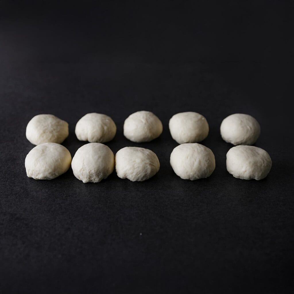 Verdeel het deeg in 10 gelijke stukken van ongeveer 80 gram. Vorm elk stuk tot een bol.