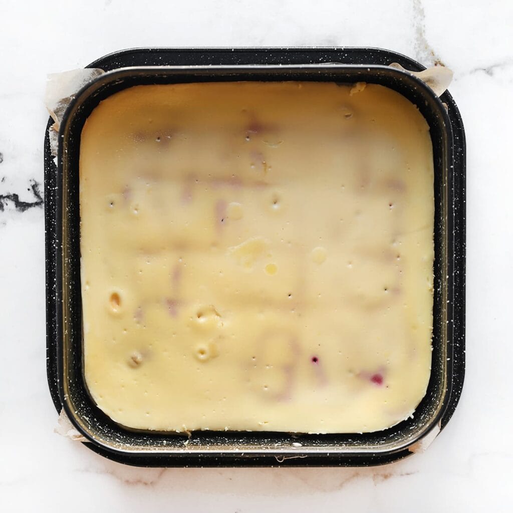 Zet de cheesecake in een voorverwarmde oven op 125 °C. Bak 60-65 minuten, of tot de zijkanten stevig zijn en het midden nog licht wiebelt. Zet de oven uit en laat de cheesecake 1 uur in de oven staan om scheuren te voorkomen. Laat de cheesecake daarna volledig afkoelen in de koelkast, het liefst een hele nacht, zodat de smaken goed kunnen intrekken.