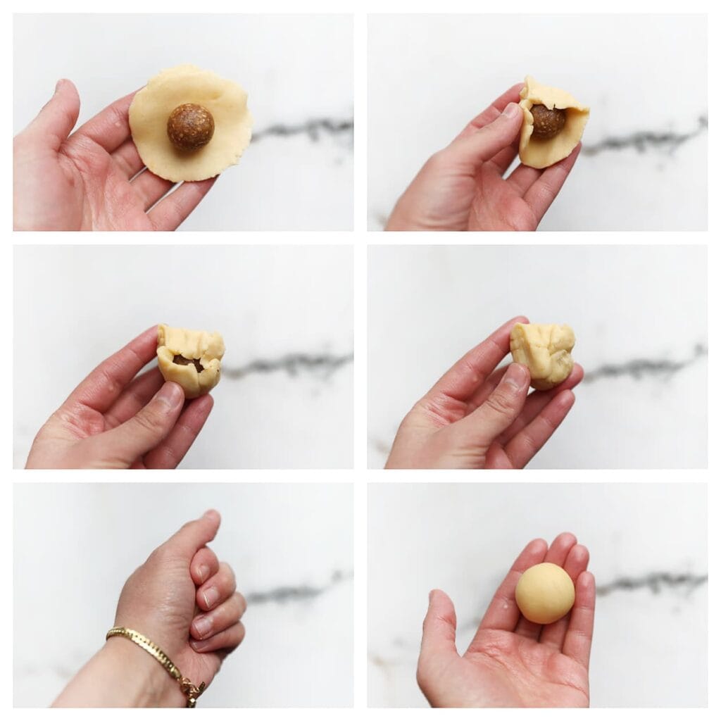 Leg een bolletje notenvulling in het midden van het deeg. Vouw het deeg goed om de vulling heen en knijp stevig dicht. Rol het opnieuw tot een gladde bal.