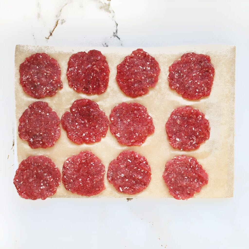 Verdeel het gehaktmengsel in 14 gelijke porties en vorm er kleine burgers van.