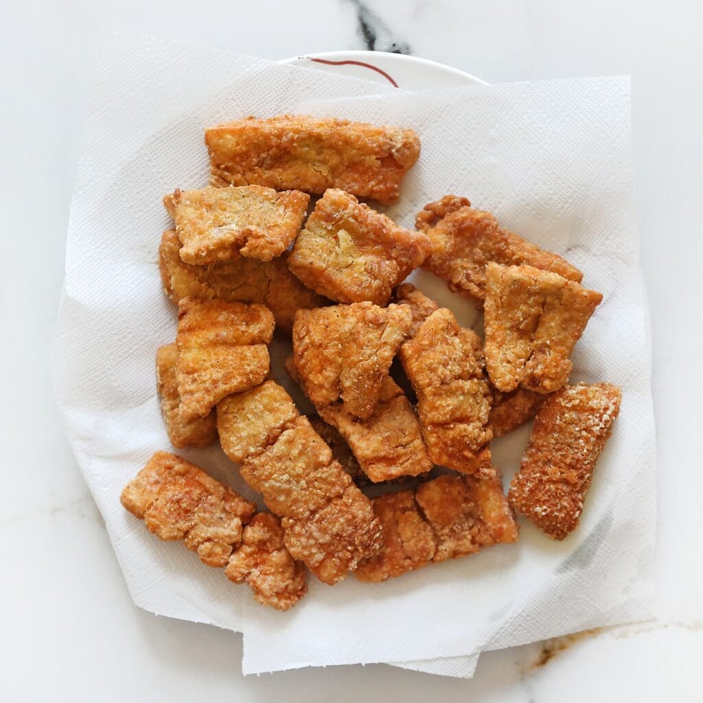 Verhit intussen een laagje zonnebloemolie in een koekenpan op middelhoog vuur (175 ℃) of gebruik een friteuse. Bak de kabeljauwstukken goudbruin en krokant. Laat ze uitlekken op een vel keukenpapier.