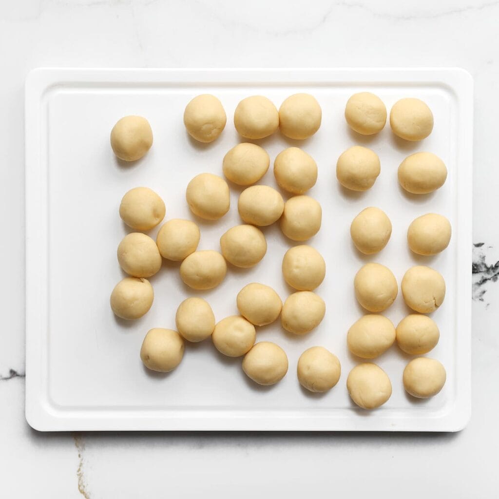 Neem 16 gram van het koekjesdeeg en rol er een balletje van. Leg het op een vel bakpapier.