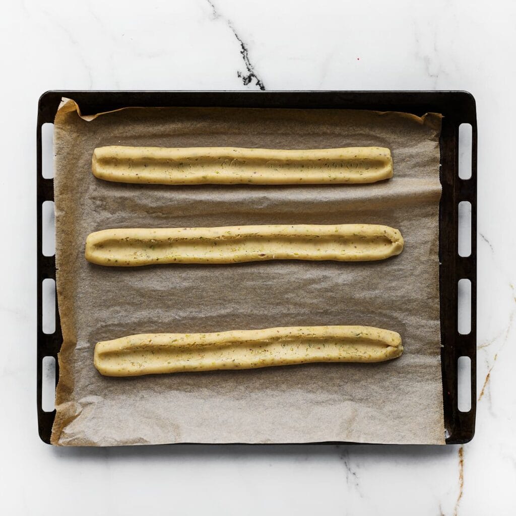 Leg de strengen op een bakplaat met bakpapier. Maak een verdieping in het midden en knijp met het tangetje langs de randen.