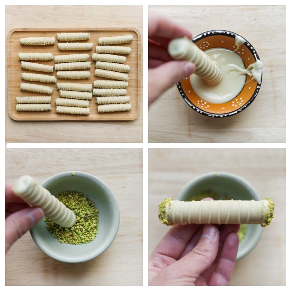 Houd een koekje vast en dip de uiteinden in de gesmolten witte chocolade. Rol direct door de pistachenoten, zodat ze goed blijven plakken. Leg op een bakplaat en laat ze op kamertemperatuur uitharden.