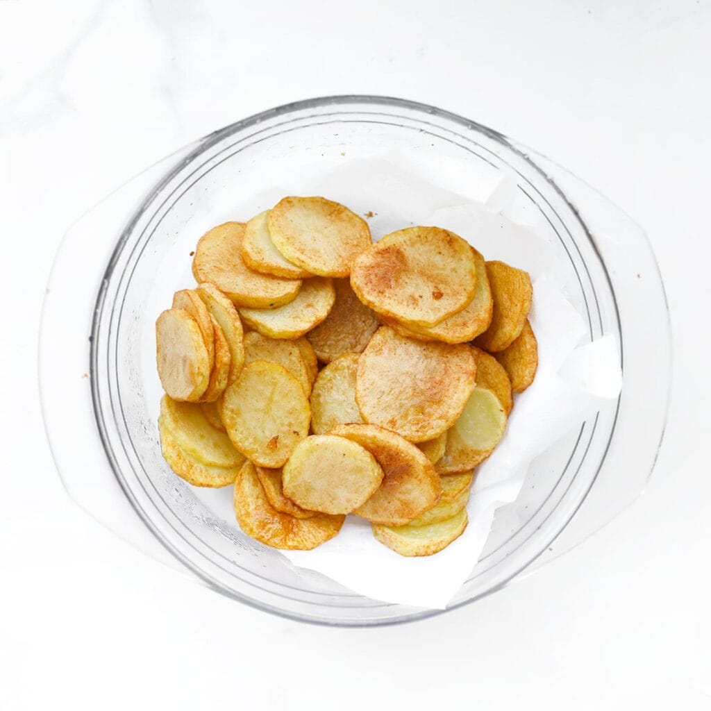 Verhit zonnebloemolie tot 170–180 °C. Frituur de aardappelplakjes in 5–7 minuten goudbruin. Laat uitlekken op keukenpapier.