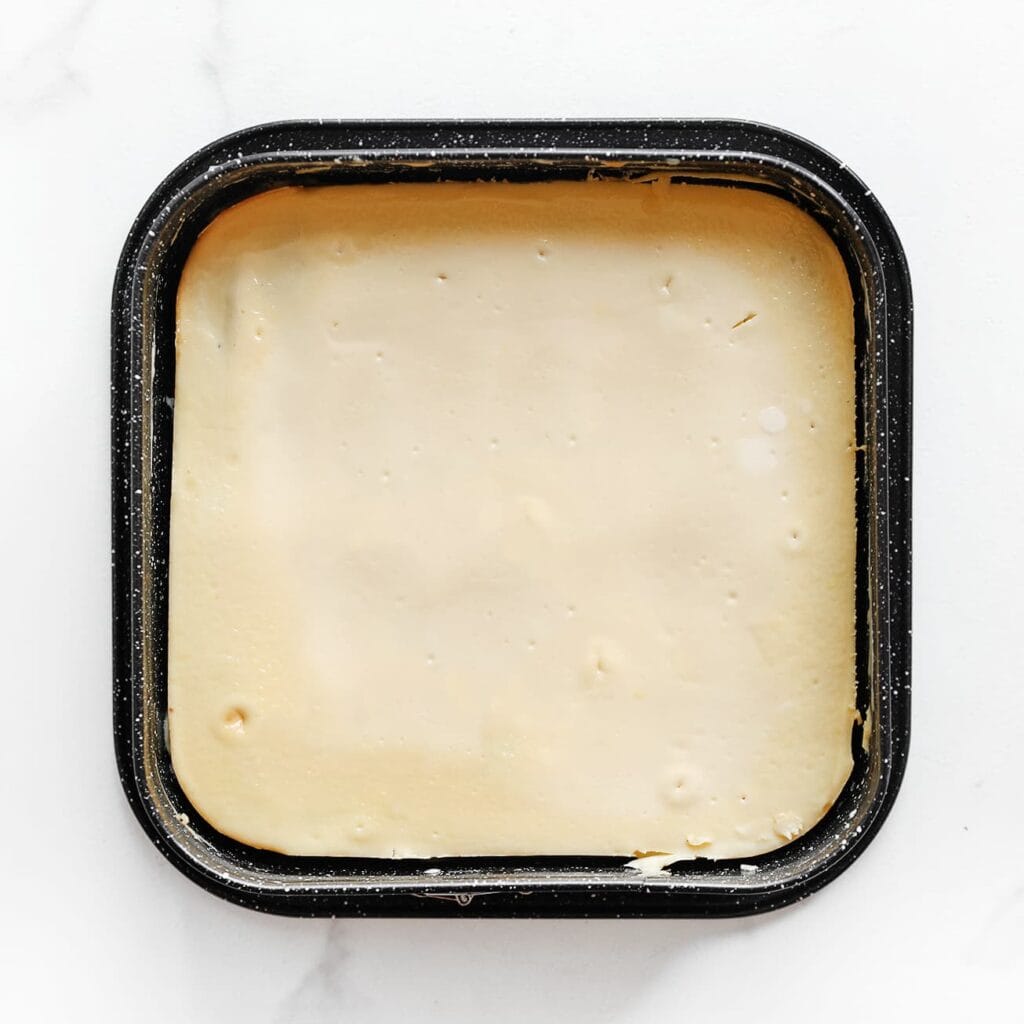 Zet de cheesecake in een voorverwarmde oven op 125 °C. Bak 60 minuten, of tot de zijkanten stevig zijn en het midden nog licht wiebelt. Zet de oven uit en laat de cheesecake 1 uur in de gesloten oven staan. Laat daarna minimaal 4 uur opstijven in de koelkast (liefst een hele nacht).