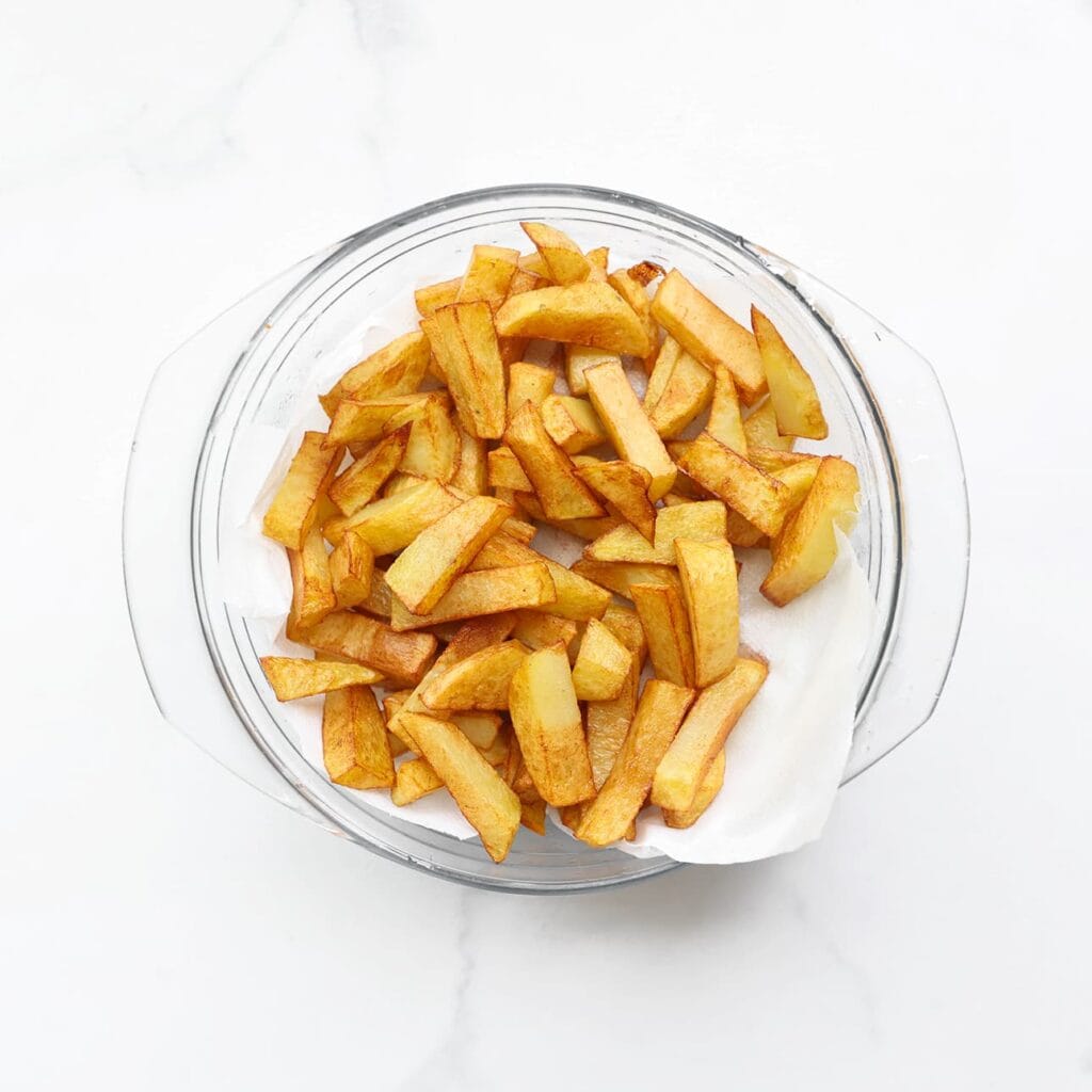 Verhit een laagje zonnebloemolie in een koekenpan op middelhoog vuur. Bak de friet in ca. 15 minuten goudbruin en gaar. Laat uitlekken op keukenpapier.