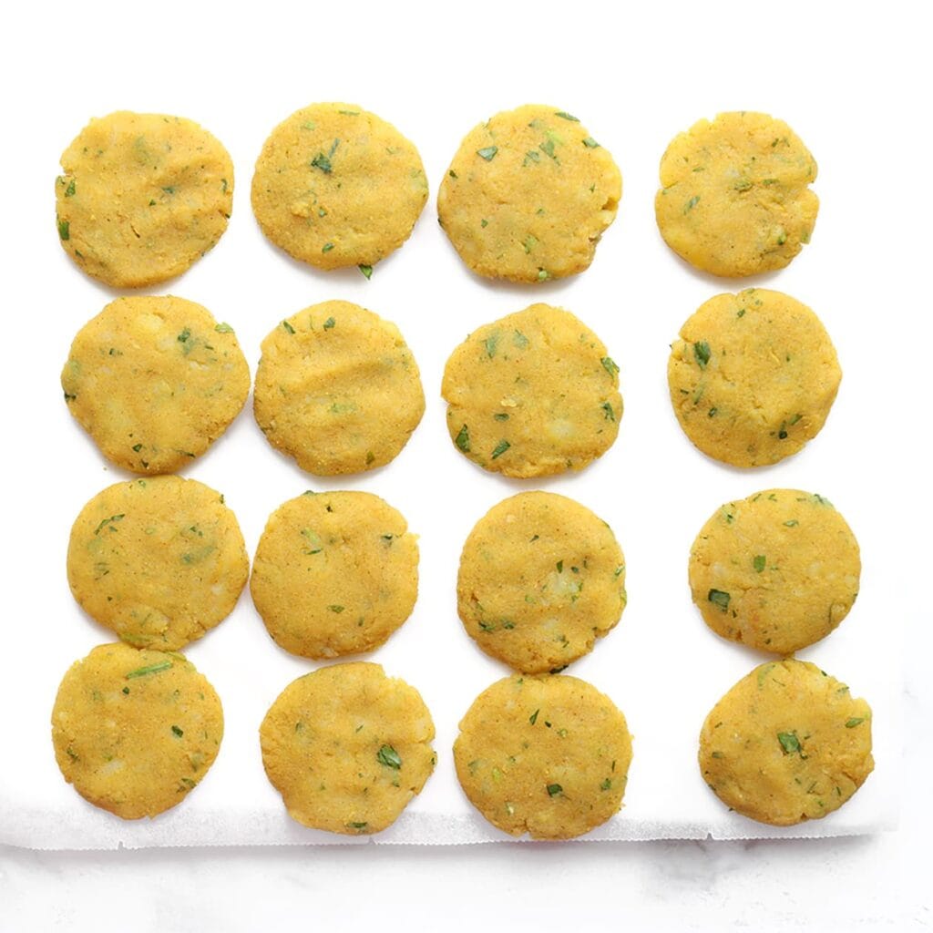 Vorm platte koekjes van ca. 4-5 cm doorsnede. Tip: maak je handen een beetje nat, zo plakt het mengsel minder. Leg de maakouda op bakpapier.